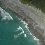 Gray-sand-beach-with-rocky-offshore-washed-by-gentle-surf-in-Alaska-Gulf-of-Alaska-Ocean-Cape-ar.jpg